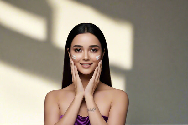 Woman applying  Bae Witch cream to her face with a neutral background